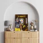 Framed canvas painting of defensive end TJ Watt with a brown background and Pittsburgh Steelers logo hanging on wall