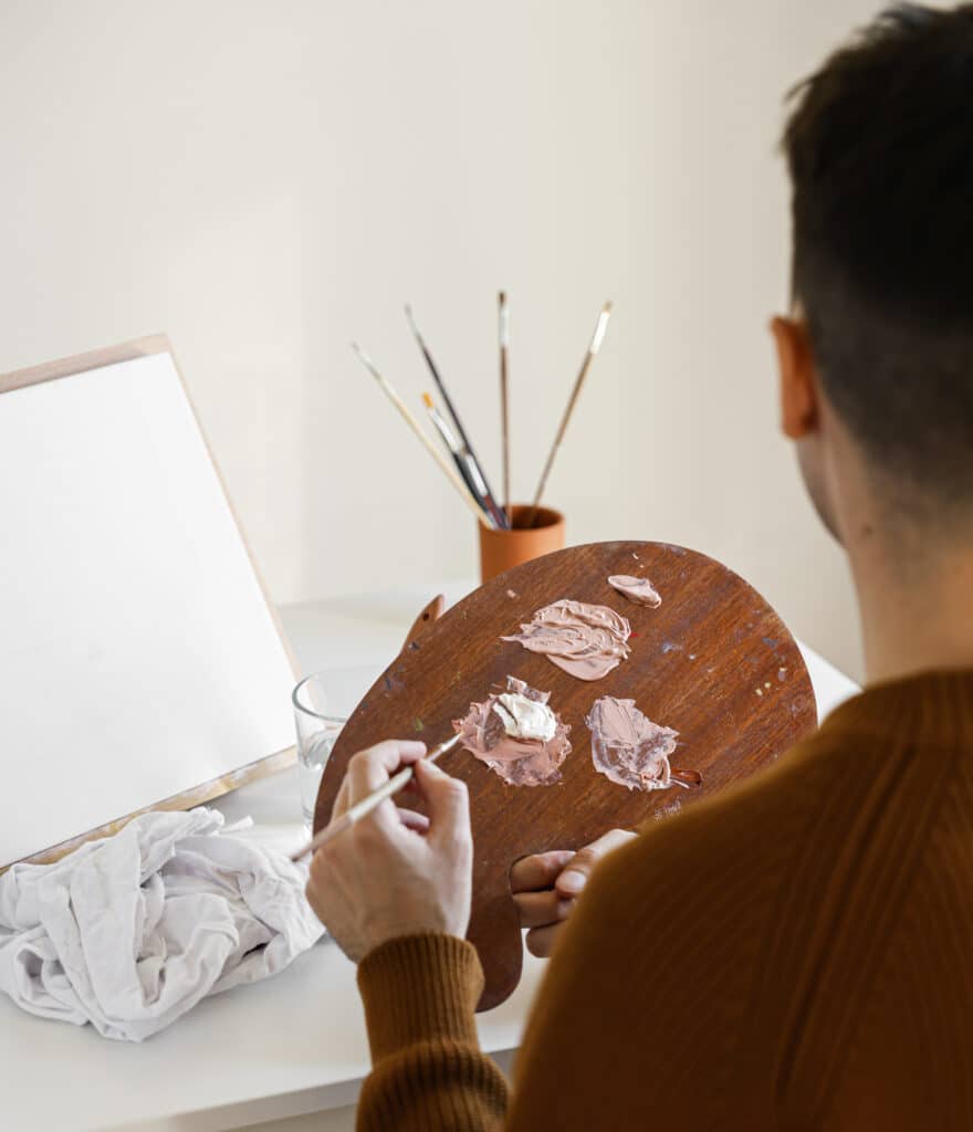 Person painting on a canvas holding a paint palette